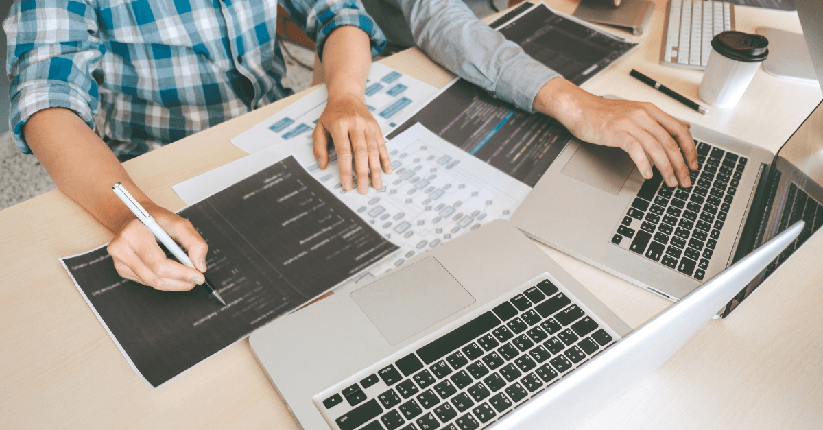 Two men with process sheets and laptops